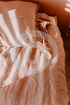 Top view of a bed with a tan-colored pink bedding and a pillow