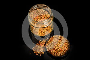 Top view of bee pollen grain in black cover next to pollen jar