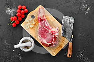 Top view of beef ribeye steak bone-in with spice on black background