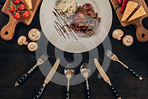 top view of beef steak on plate and utensil