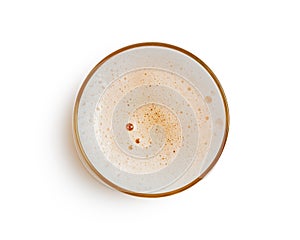 Top view of beer bubbles in glass cup on white background.