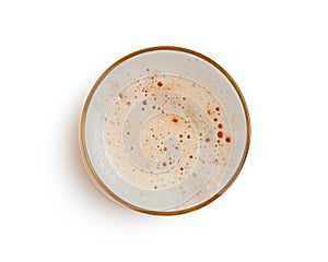 Top view of beer bubbles in glass cup on white background.