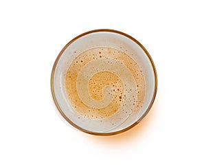 Top view of beer bubbles in glass cup on white background.