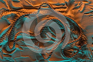 Top view of bend rope and traces of rope on the sand with orange and blue lights.