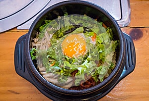 Top view of Bibimbap, traditional Korean food served in warm bowl and cooked by mixed rice with vegetables, eggs and meat.