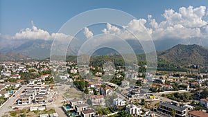 Top view of the big city. Residential houses. Urbanization. Green mountains and clouds in the background. Photography