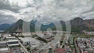 Top view of the big city. Residential houses. Urbanization. Green mountains and clouds in the background. Timelapse