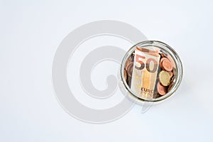 Top view bill and coin in euro collect in glass transparent bottle on white background ands space for text.  Money save concept