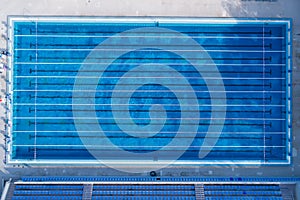 Top view, bird eye view of swimming pool with marked lanes and starting platform.