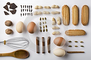 Top view of biscuits, cinnamon, cardamon, peanuts, eggs, nuts, chocolate, kithcen utensils in a row, abreast.Preparing ingredients