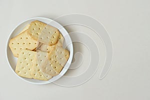 top view of  biscuits on white round ceramic dish placed on beige background with copy space