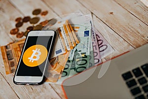 Top view of bitcoin icon on smart phone screen, euro banknotes a