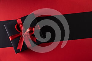 Top view of black christmas boxes with red ribbon on black background with copy space for text. black Friday and Boxing Day