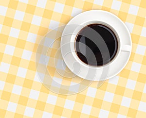 Top view of black coffee cup on checked tablecloth