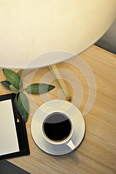 Top view of Black Coffee on Wooden Table with Lighting from Table Lamp photo