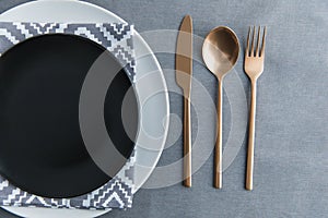 top view of black empty plate, napkin and old fashioned tarnished cutlery on tabletop