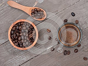top view of black espresso coffee in a glass cup with coffee beans on a wooden table
