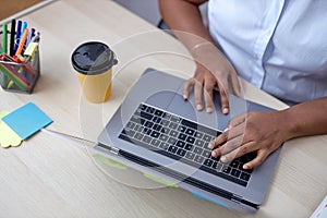 top view on black female hands typing on laptop keyboard, working online on desk