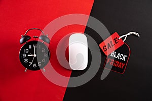 Top view of Black Friday Sale text with black gift box with Alarm clock, white mouse and red paper tag on red black background.