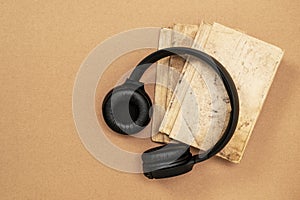 Top view of black headphones and books on cardboard background