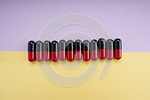 Top view - Black and red medicine pill capsule over pastel background