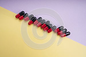 Top view - Black and red medicine pill capsule over pastel background