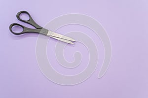 Top view of black scissors isolated on light violet background