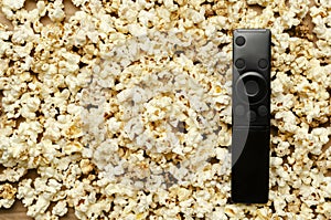Top view of black tc clicker on the tasty sweet popcorn.Empty space