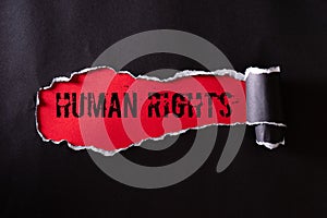 Top view of Black torn paper and the text HUMAN RIGHTS on a red background. Human rights concept