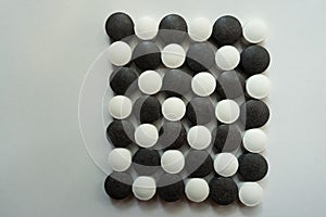 Top view of black and white pills in shape of checkerboard