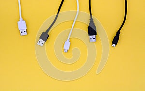 Top view black and white USB cables on yellow background with copy space, flat lay