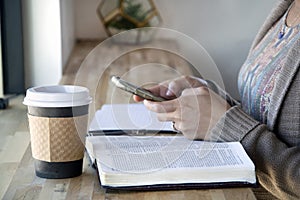 Top view of Black woman studies her bible and uses phone