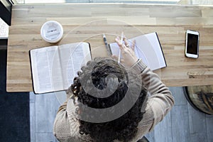 Top view of Black woman studies her bible and uses phone