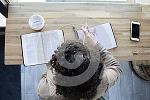 Top view of Black woman studies her bible and uses phone photo