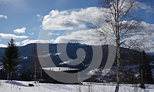 Top view of Black wooden house with panoramic view of snowy Carpathian mountains