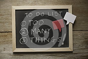 Top view of a blackboard with a chalk written with To do list : too many things! in numbers