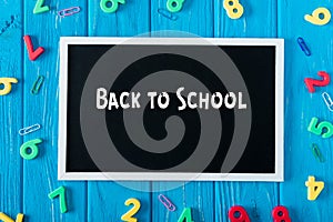 top view of blackboard with lettering back to school paper clips and colorful numbers on blue wooden