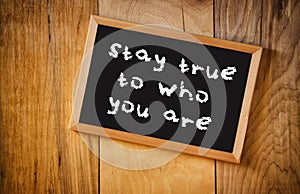 Top view of blackboard with the phrase stay true to who you are, over wooden background