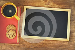 Top view of blank blackboard next to coffee cup over wooden table