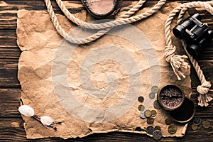 top view of blank crumpled paper with compass, binoculars and rope on rustic