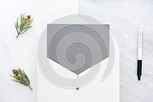 Top view of blank grey card in white envelop with pen and pine l photo