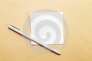 Top view of blank note paper with pen on beige background