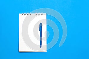 Top view of blank note paper with pen on blue wood table for background.