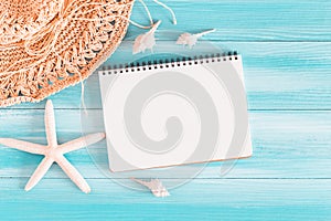 Top view of blank notebook on blue wood table, sea shells and starfish on a blue wooden background, Summer concept