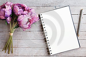 Top view of blank notebook, clock, pen and green plant on wooden pallet background