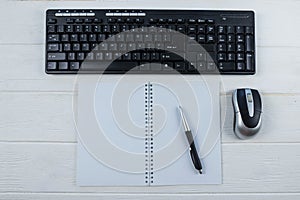 Top view of a blank notepad with a pen, keyboard and computer mouse