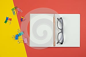 Top view of blank open notebook with pencil and stationery items and eyeglasses