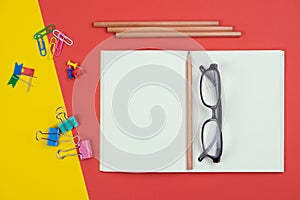 Top view of blank open notebook with pencil and stationery items and eyeglasses