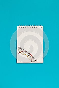 Top view of blank spiral notebook and glasses
