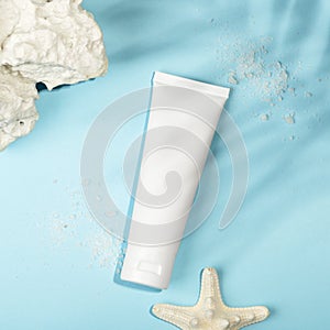 Top view of blank unbranded tube, starfish, sea salt and corals. White container for cream, sunscreen, scrub, serum or lotion,